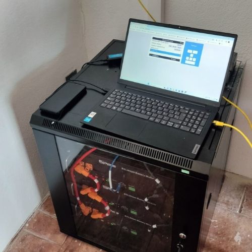 Rack con baterías para fotovoltaica aislada de litio, con un portátil encima para configurar y monitorizar el sistema de energía solar aislada